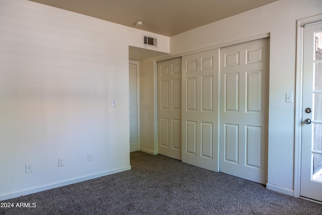 unfurnished bedroom with dark colored carpet and a closet