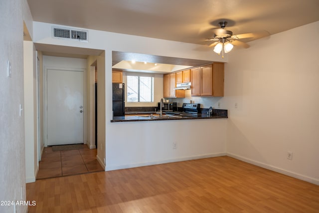 kitchen with light wood-type flooring, black fridge, stainless steel range with electric cooktop, kitchen peninsula, and ceiling fan