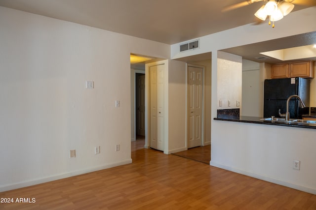 kitchen featuring ceiling fan, black fridge, sink, and light hardwood / wood-style floors