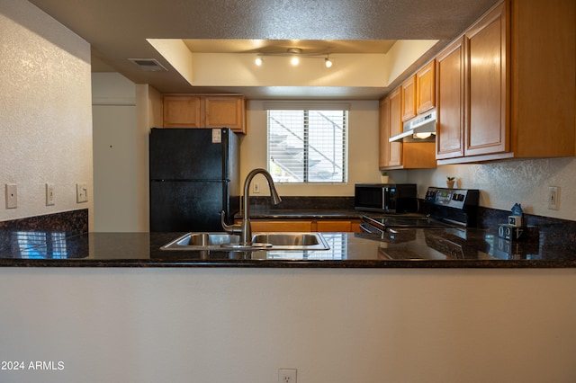 kitchen featuring dark stone countertops, kitchen peninsula, black appliances, a tray ceiling, and sink