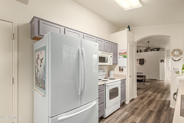 kitchen featuring gray cabinets, wood finished floors, arched walkways, white appliances, and a ceiling fan