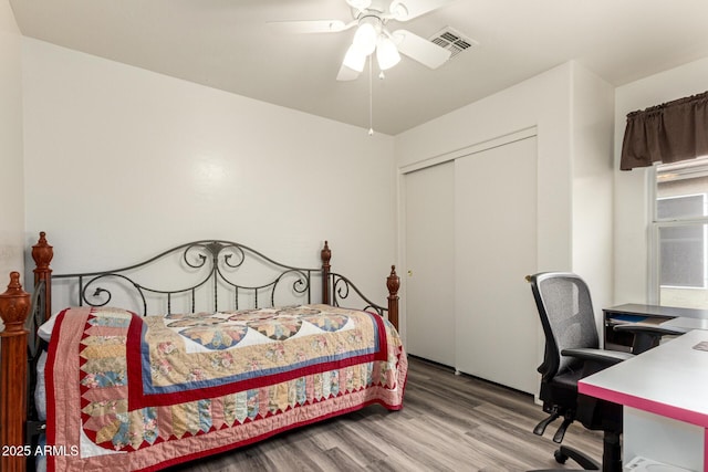 bedroom with wood finished floors, visible vents, a closet, and ceiling fan