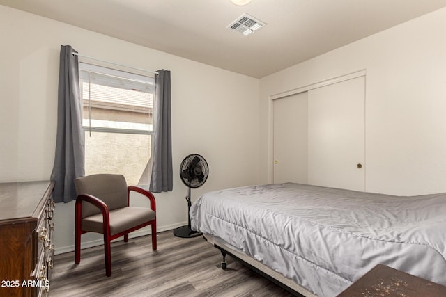 bedroom featuring wood finished floors, visible vents, a closet, and baseboards