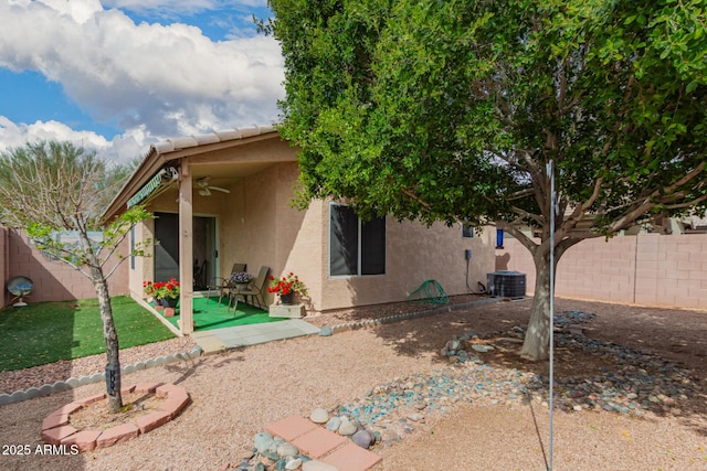 rear view of property featuring stucco siding, a ceiling fan, a patio, central AC, and a fenced backyard