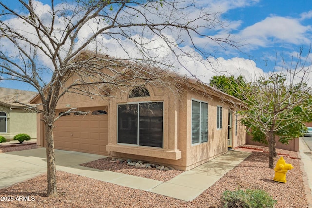 view of front of home featuring concrete driveway, an attached garage, and stucco siding