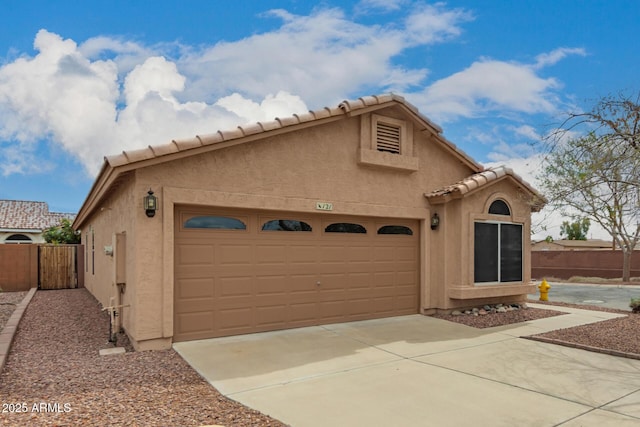 view of front of house with stucco siding, driveway, and fence