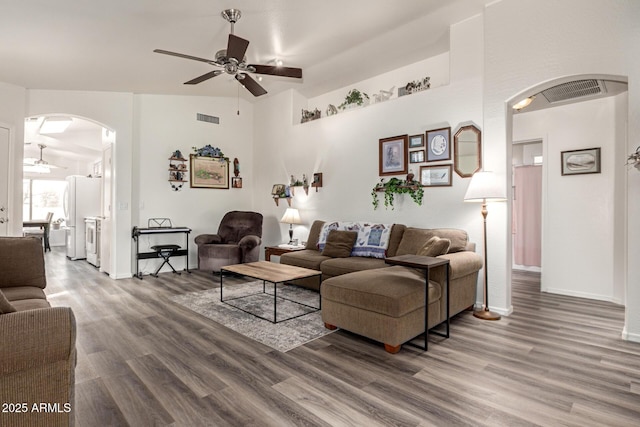 living area with wood finished floors, visible vents, arched walkways, and ceiling fan