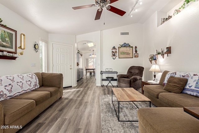 living area with visible vents, vaulted ceiling, wood finished floors, arched walkways, and a ceiling fan