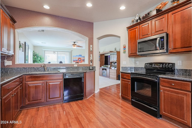 kitchen featuring light wood-type flooring, ceiling fan, sink, black appliances, and dark stone countertops