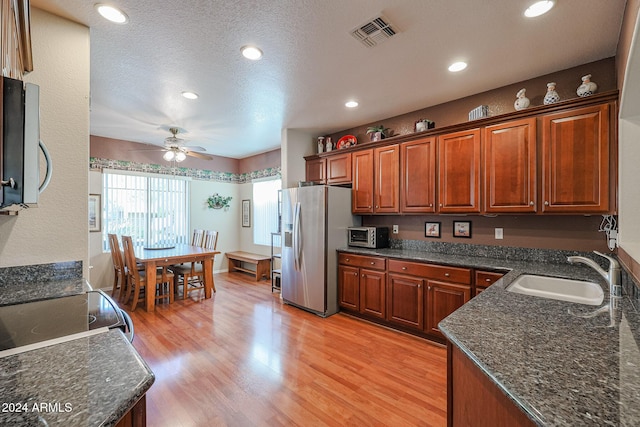 kitchen with ceiling fan, sink, stainless steel fridge, light hardwood / wood-style floors, and a textured ceiling