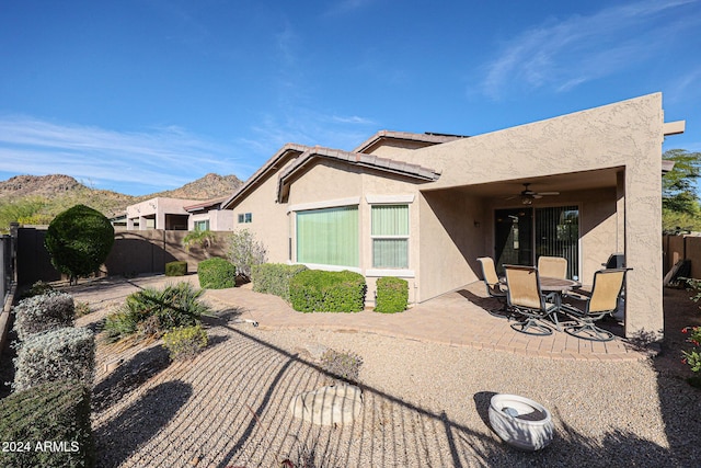 rear view of house featuring ceiling fan, a mountain view, and a patio