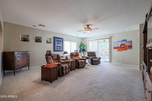 living room with ceiling fan, light colored carpet, and a textured ceiling