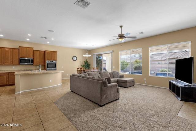 living room with sink, light tile patterned floors, and ceiling fan with notable chandelier