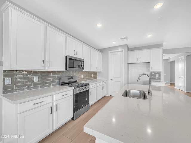 kitchen featuring light stone countertops, stainless steel appliances, sink, light hardwood / wood-style flooring, and white cabinets