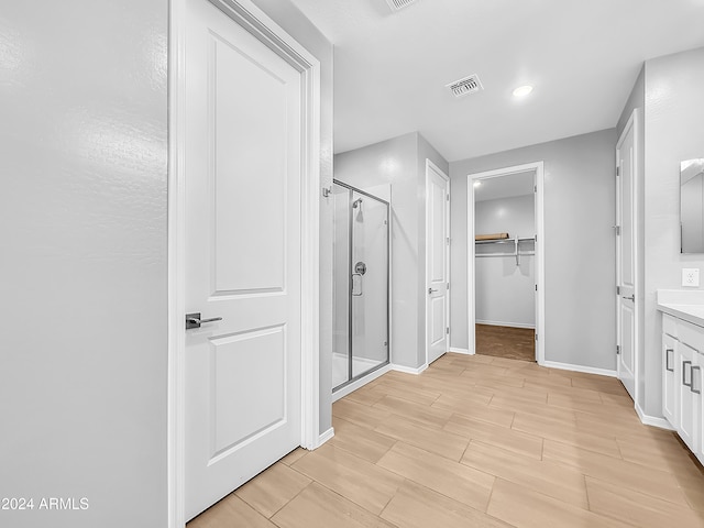 bathroom featuring hardwood / wood-style floors, vanity, and a shower with shower door