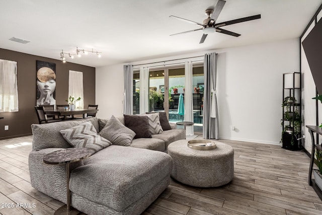 living room with ceiling fan, wood finished floors, visible vents, and baseboards