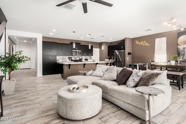 living area featuring visible vents, a ceiling fan, light wood-style flooring, and recessed lighting