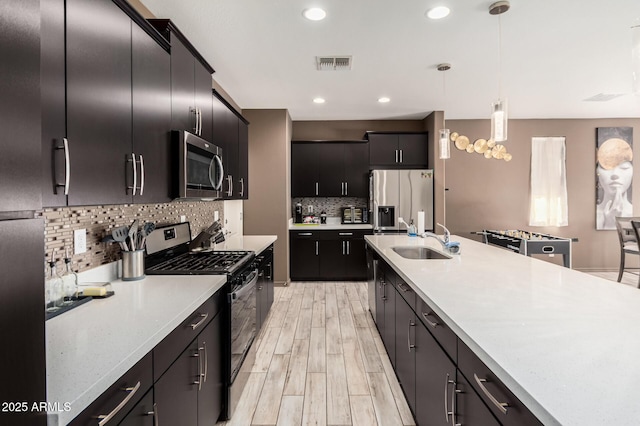 kitchen featuring visible vents, hanging light fixtures, stainless steel appliances, light countertops, and a sink