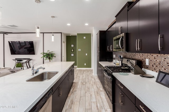 kitchen featuring tasteful backsplash, light countertops, stainless steel microwave, black range with gas stovetop, and a sink