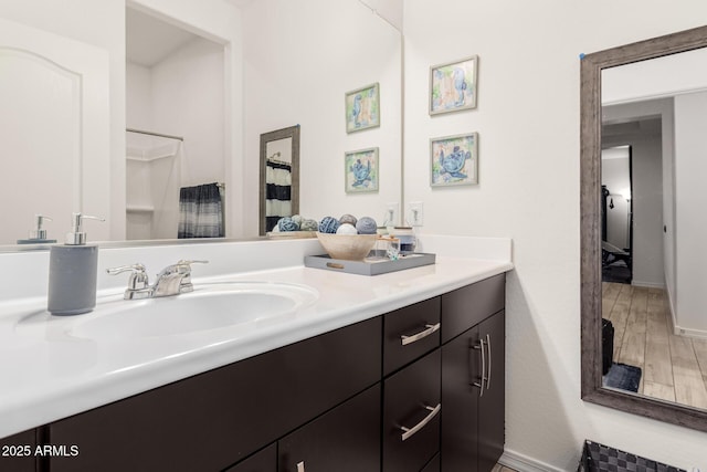 bathroom with baseboards, wood finished floors, and vanity