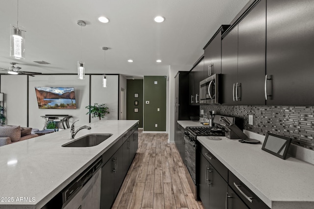 kitchen with decorative backsplash, appliances with stainless steel finishes, open floor plan, dark cabinetry, and a sink