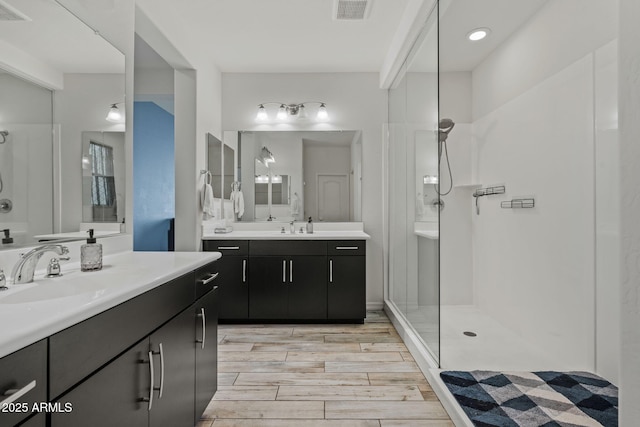 bathroom featuring visible vents, a sink, and walk in shower