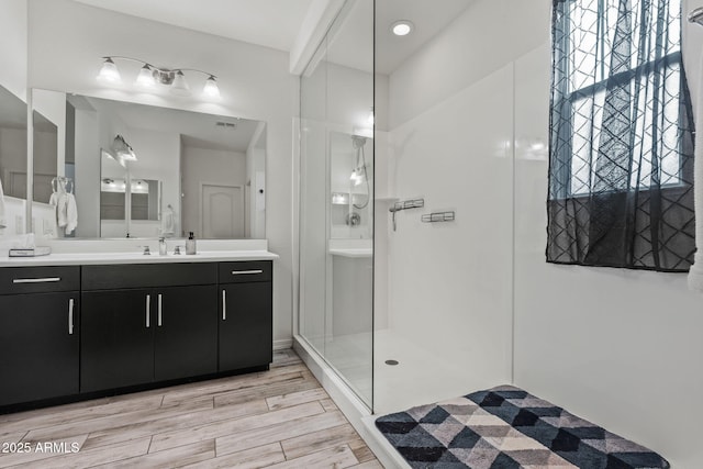 bathroom featuring wood finish floors, a stall shower, and vanity
