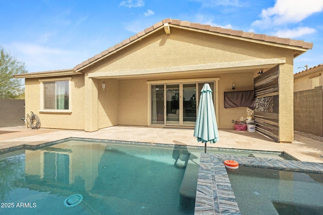 back of property featuring a fenced in pool, a tile roof, stucco siding, a patio area, and fence