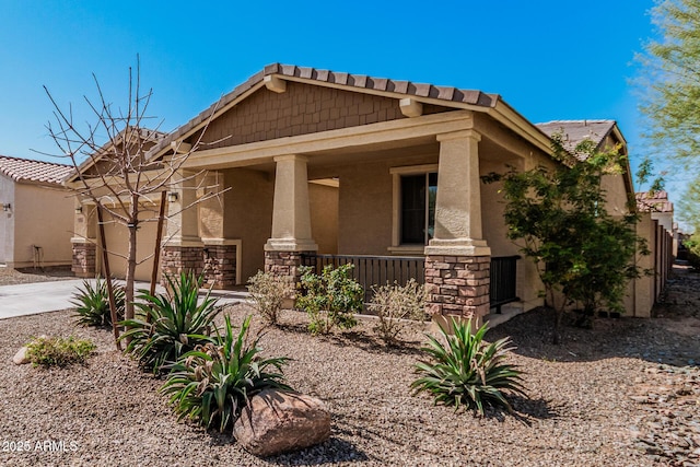 craftsman house with a garage, concrete driveway, stone siding, covered porch, and stucco siding