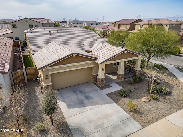 view of front of property featuring driveway, a residential view, a tiled roof, fence, and stucco siding