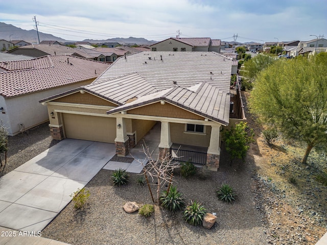 view of front of home featuring covered porch, stone siding, concrete driveway, a tiled roof, and stucco siding