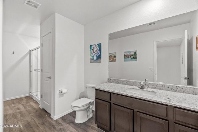 bathroom featuring hardwood / wood-style floors, vanity, a shower with door, and toilet