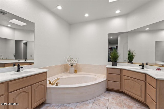 bathroom featuring a bathing tub, vanity, a skylight, and tile patterned floors