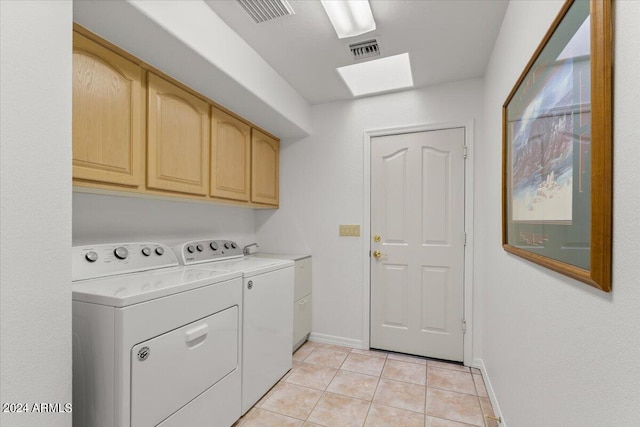 laundry room featuring light tile patterned flooring, washing machine and clothes dryer, a skylight, and cabinets