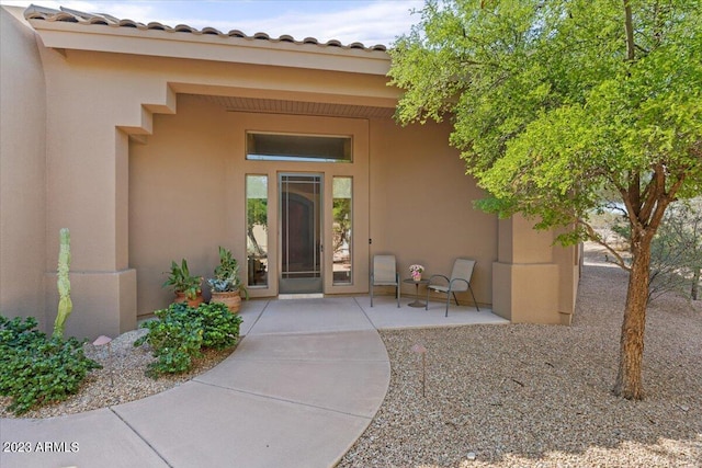 view of exterior entry with a patio