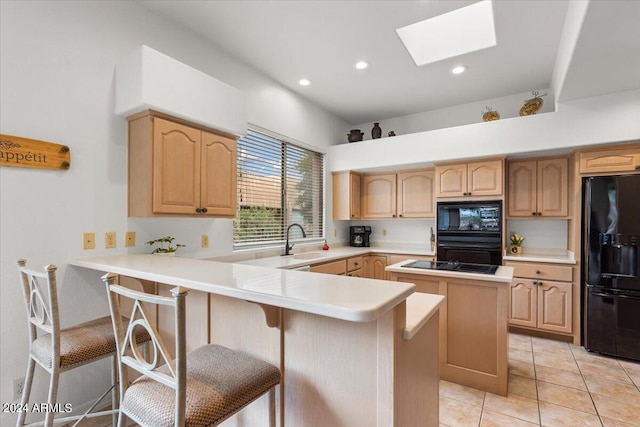 kitchen with a center island, kitchen peninsula, a kitchen bar, black appliances, and a skylight