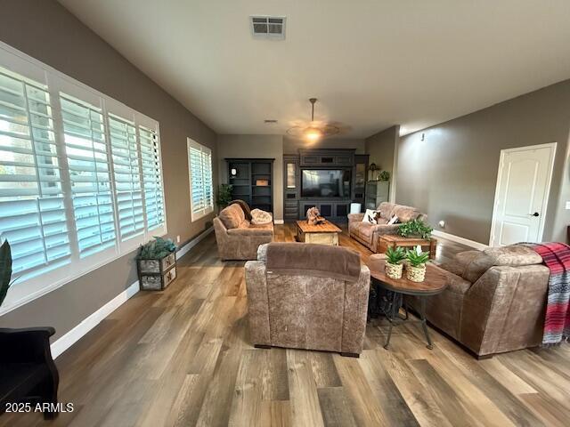 living room featuring baseboards, visible vents, and wood finished floors