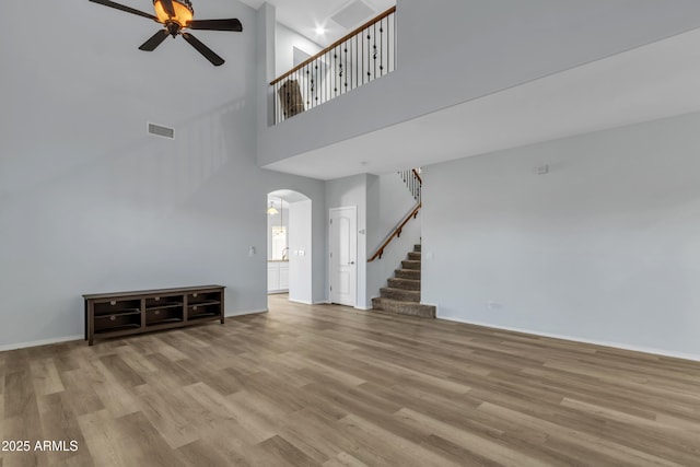 unfurnished living room with a high ceiling, light hardwood / wood-style flooring, and ceiling fan