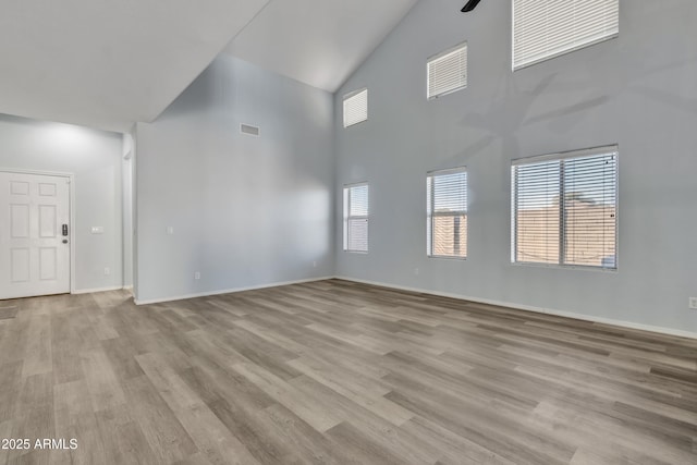 unfurnished living room with light hardwood / wood-style floors and a high ceiling