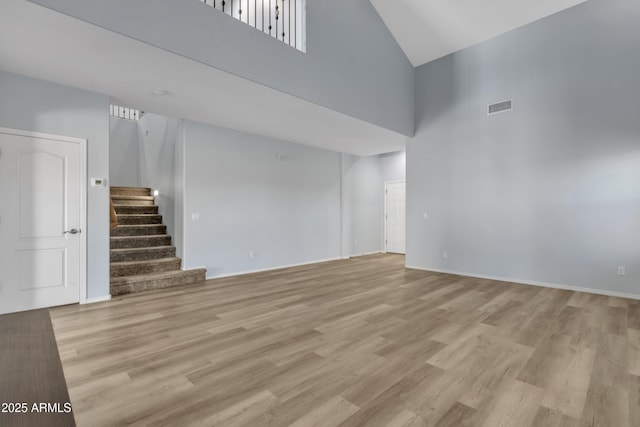 unfurnished living room with a towering ceiling and light wood-type flooring