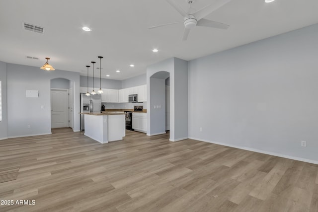 kitchen featuring light wood-type flooring, stainless steel appliances, pendant lighting, a center island, and white cabinetry