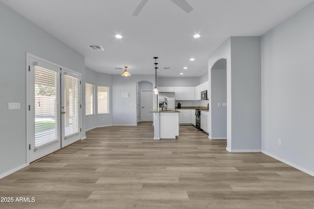 kitchen with appliances with stainless steel finishes, ceiling fan, decorative light fixtures, a center island with sink, and white cabinetry