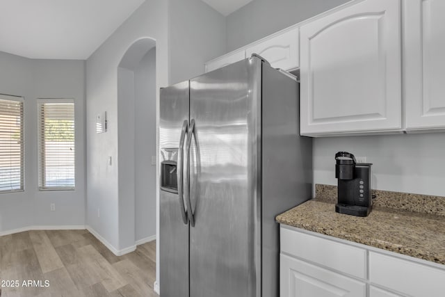 kitchen with light stone countertops, stainless steel refrigerator with ice dispenser, light hardwood / wood-style flooring, and white cabinetry