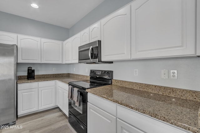 kitchen featuring white cabinets, light hardwood / wood-style floors, stainless steel appliances, and dark stone counters