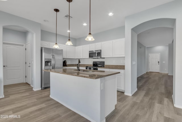 kitchen with appliances with stainless steel finishes, a kitchen island with sink, sink, decorative light fixtures, and white cabinetry