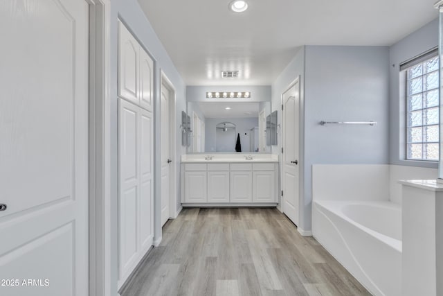 bathroom featuring a bathing tub, vanity, and wood-type flooring