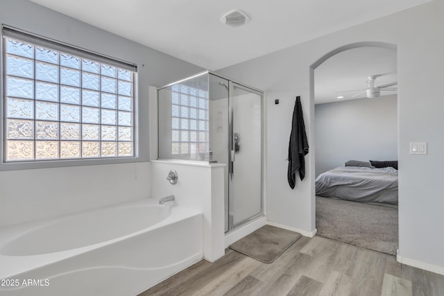 bathroom featuring hardwood / wood-style flooring, ceiling fan, and shower with separate bathtub