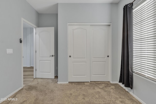 unfurnished bedroom with a closet and light colored carpet