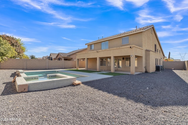 rear view of property featuring an in ground hot tub, central AC, and a patio area