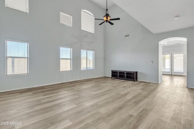 unfurnished living room featuring ceiling fan, light hardwood / wood-style flooring, and a high ceiling